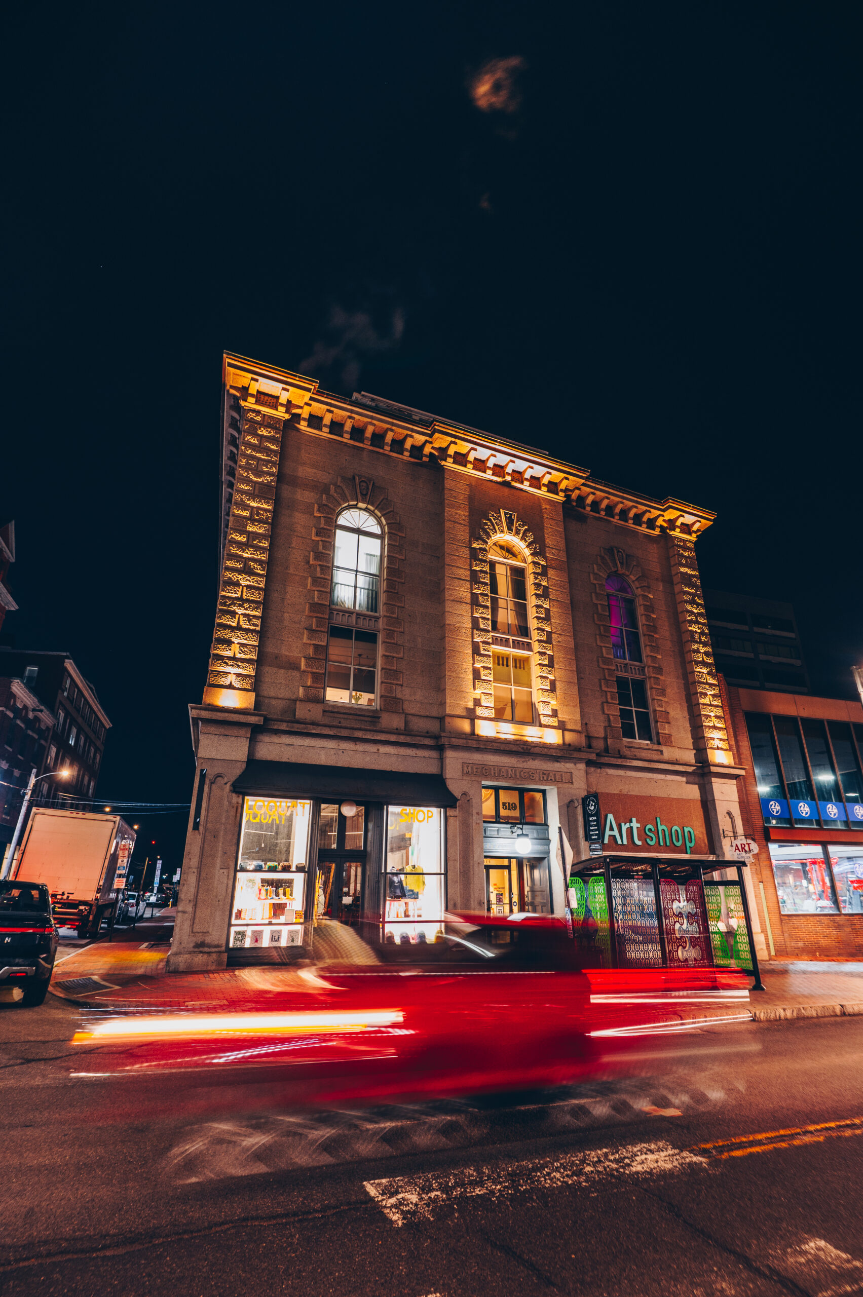 Historic Italiante building on Congress Street lit up at night featuring arcitectural details and the red tail lights of cars driving by